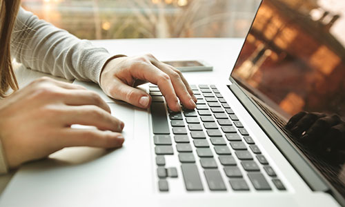 Person arbeitet am Laptop mit geöffnetem Bildschirm.